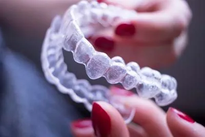 woman holding her new clear aligners she got from Sandia View Family Dental