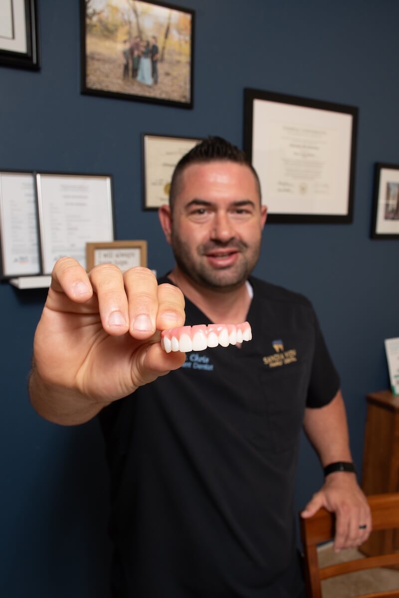 Dr. Chris Christensen holding a full arch dental implant at Sandia View in Rio Rancho NM.