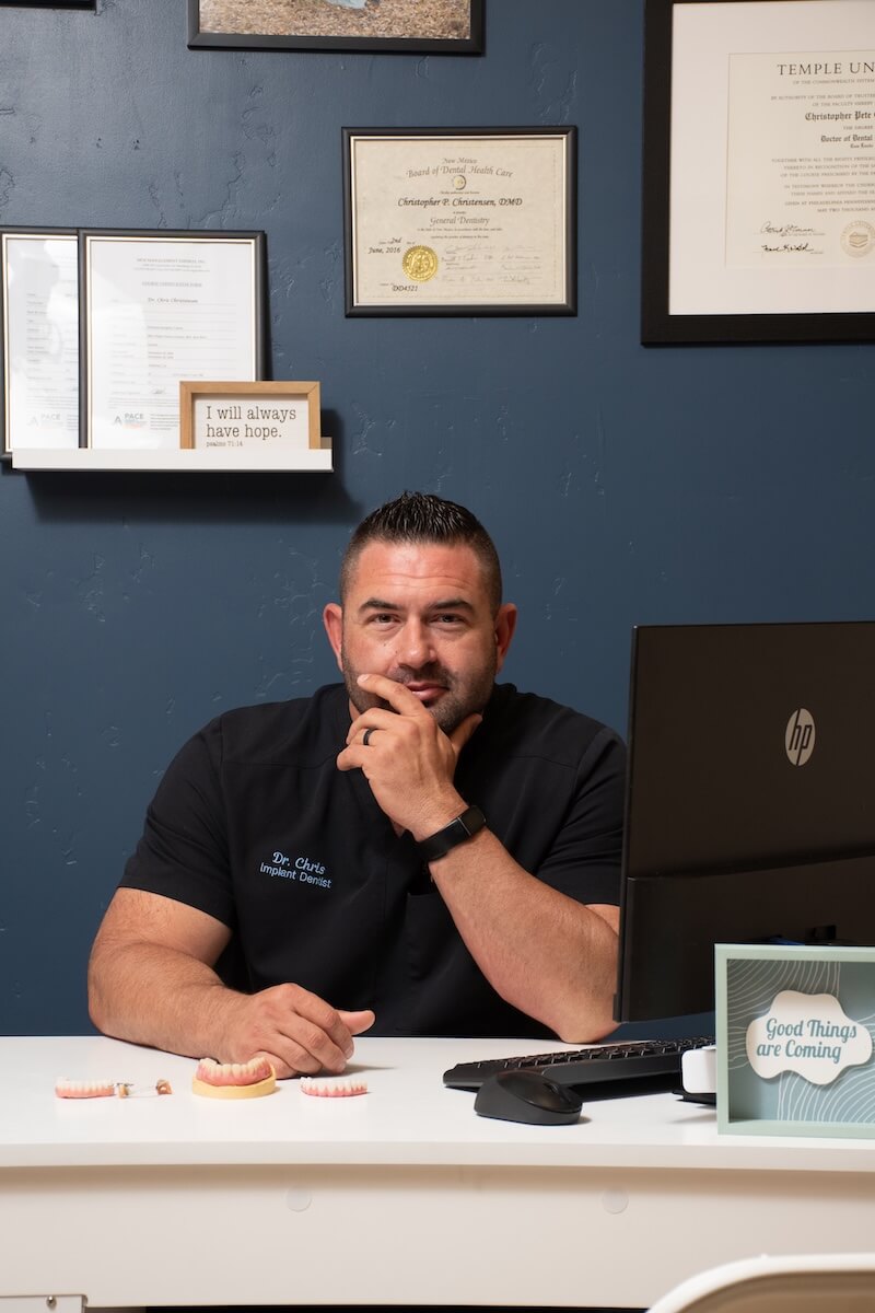 Dr. Chris Christensen at his desk with implants and dentures in front of him at Sandia View in Rio Rancho NM.